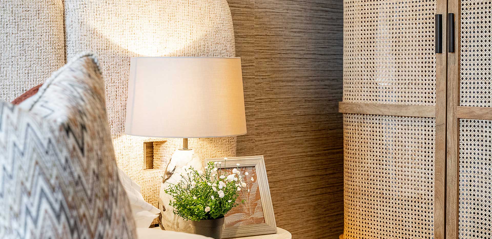 Closeup of bedside, padded fabric headboard, wooden designer wardrobe.