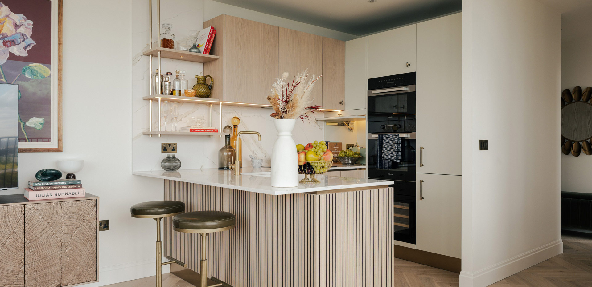 Kitchenette with attached island, beige cupboard panels and white countertops.