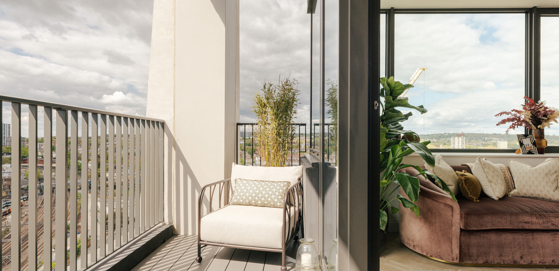View of balcony with outdoor seating and indoor sofa adjacent.