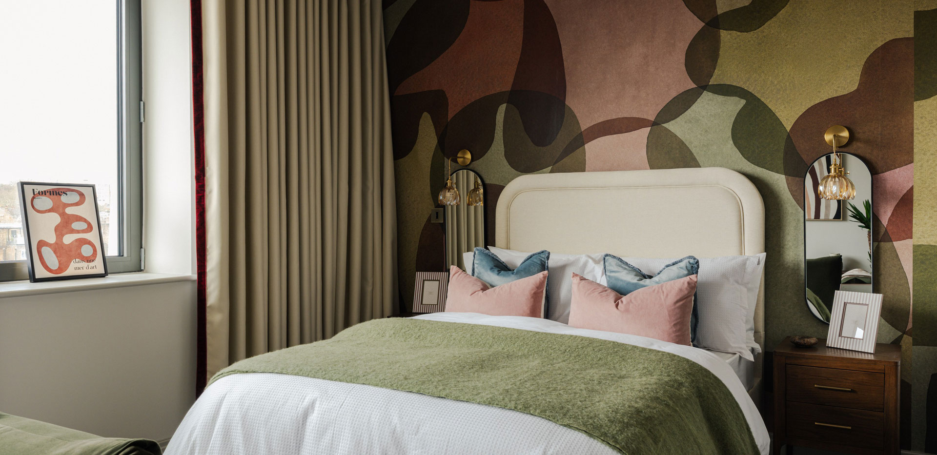 Double bed, bedside tables, patterned wallpaper.