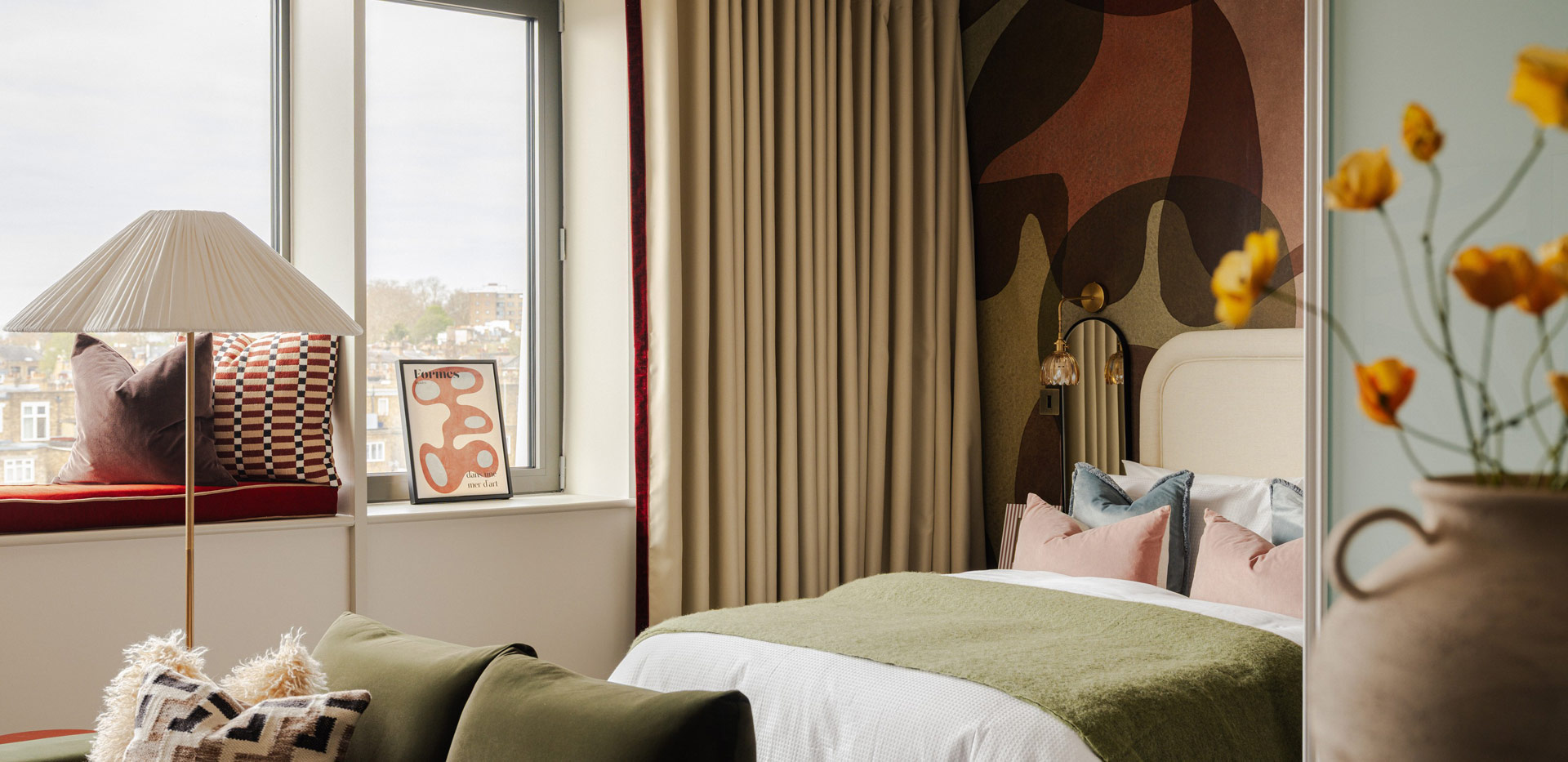 Double bed, bedside tables, patterned wallpaper.