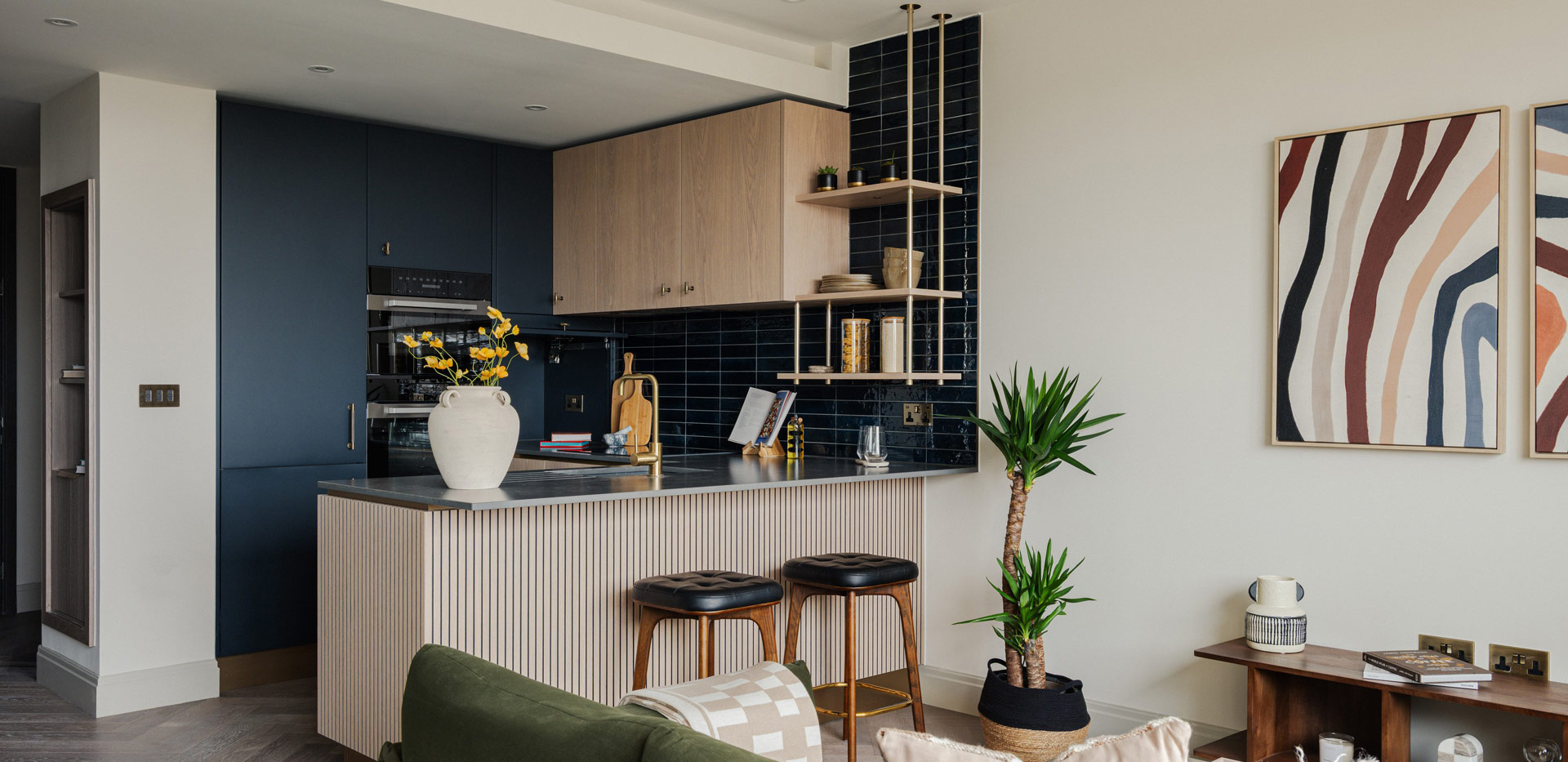 Kitchen with attached island, dark blue splashback tiles and navy blue panels.