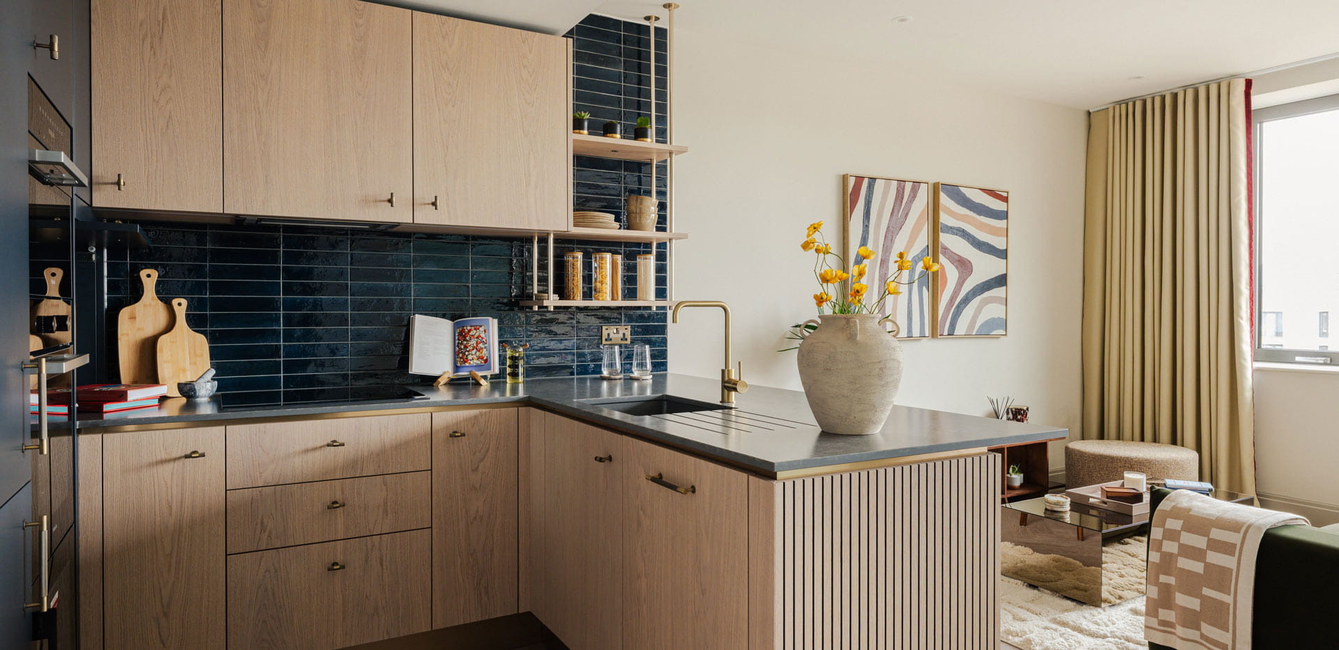 Kitchen with attached island, dark blue splashback tiles, grey countertops.