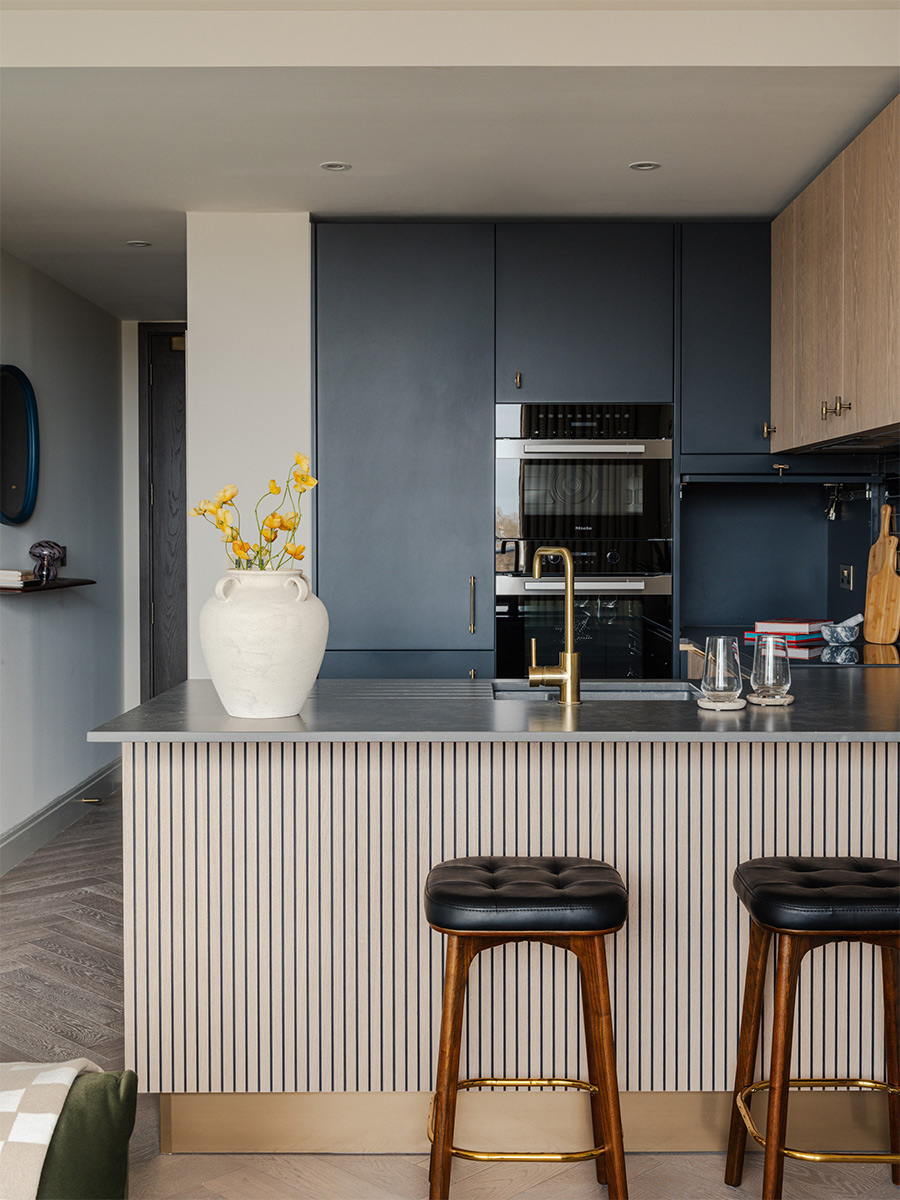 Kitchen with attached island, navy blue panels, grey countertops.