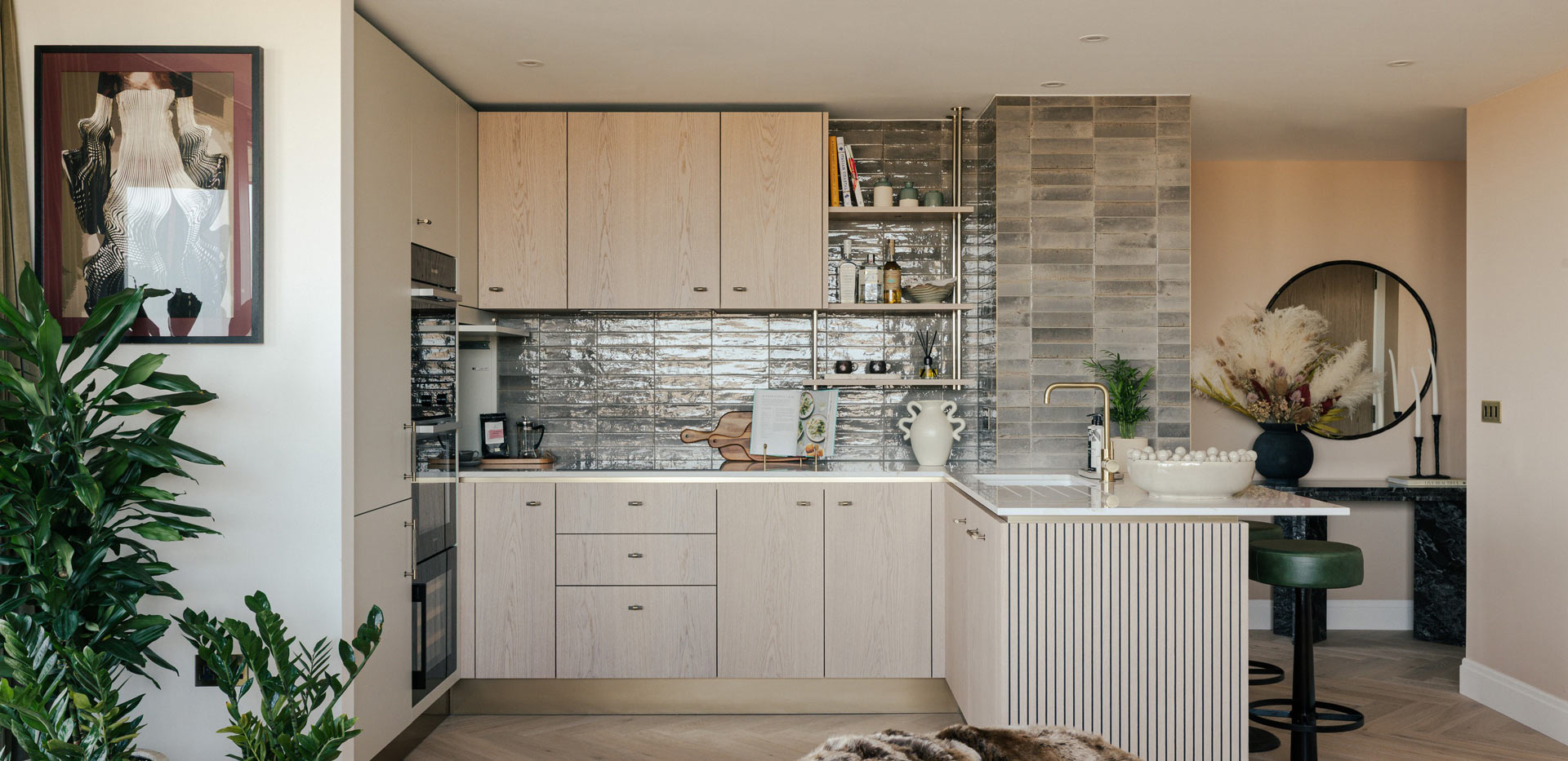 Kitchenette with breakfast island, beige-cream cupboard panels and white countertops.