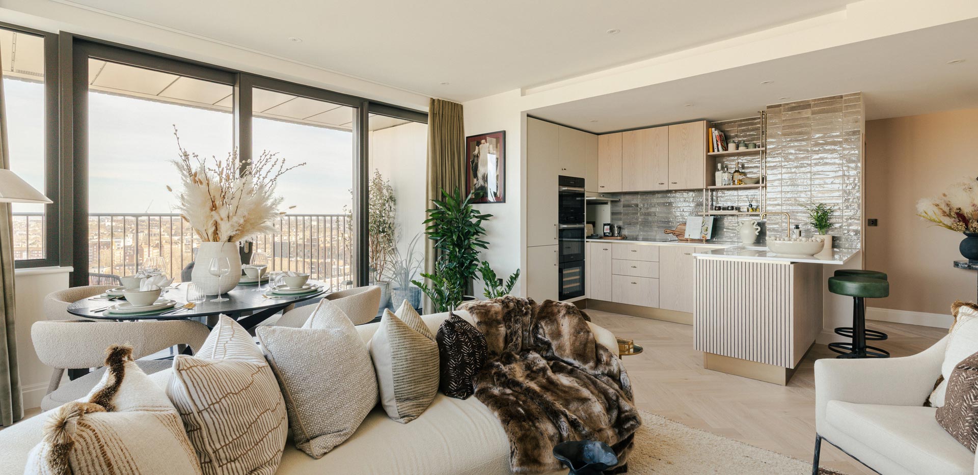 Living space in foreground, kitchen with island, beige and cream design palette.