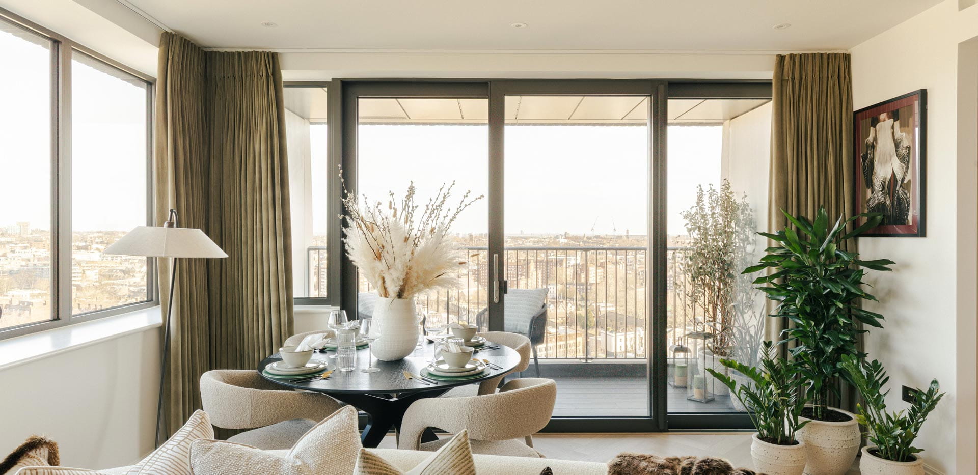 View of living space and dining table with balcony door and view in background.