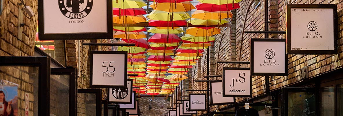 An image of shops in Camden with colourful umbrellas above the walkway