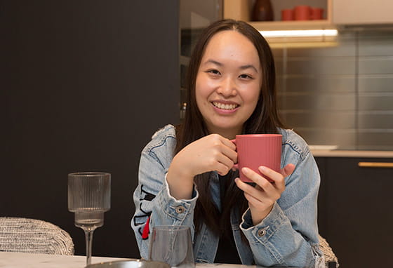 An image of Aurora having a hot drink in their new kitchen