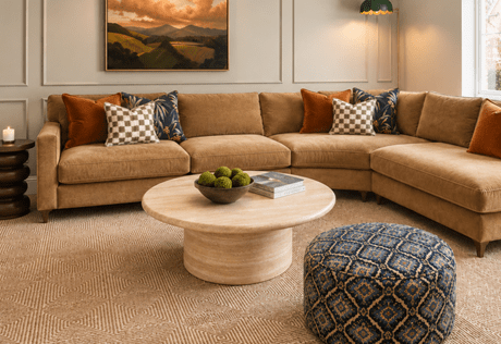 Furnished living space with fabric L-shaped sofa, round coffee table, carpet flooring.