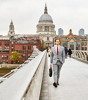 A businessman walking over a bridge 
