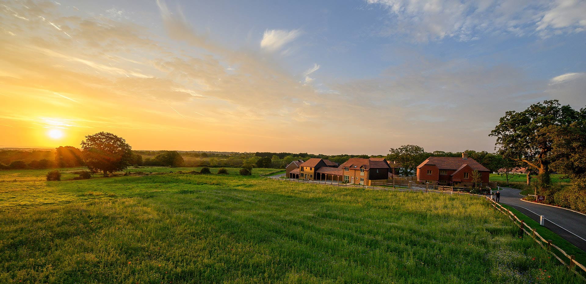 Exterior image of Farmstead, showing a beautiful sunset and vast open green spaces. 