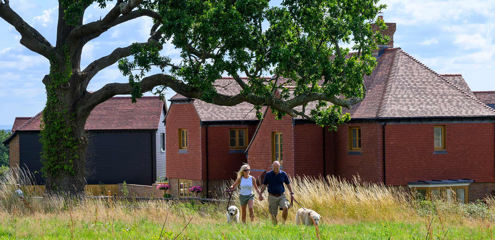 An exterior image of Farmstead residents walking their dogs around the beautiful open landscape that surrounds the development