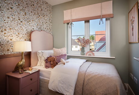 Single bed next to window, with flower-wallpaper and light grey walls