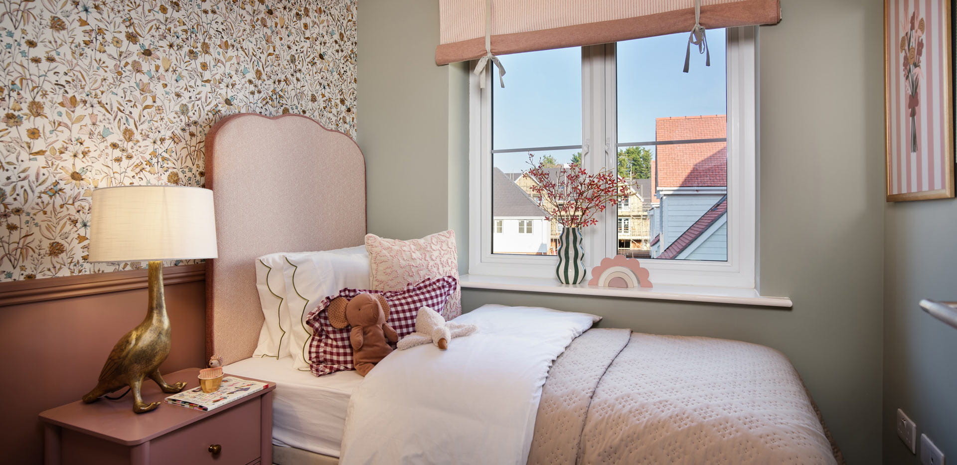 Single bed next to window, with flower-wallpaper and light grey walls