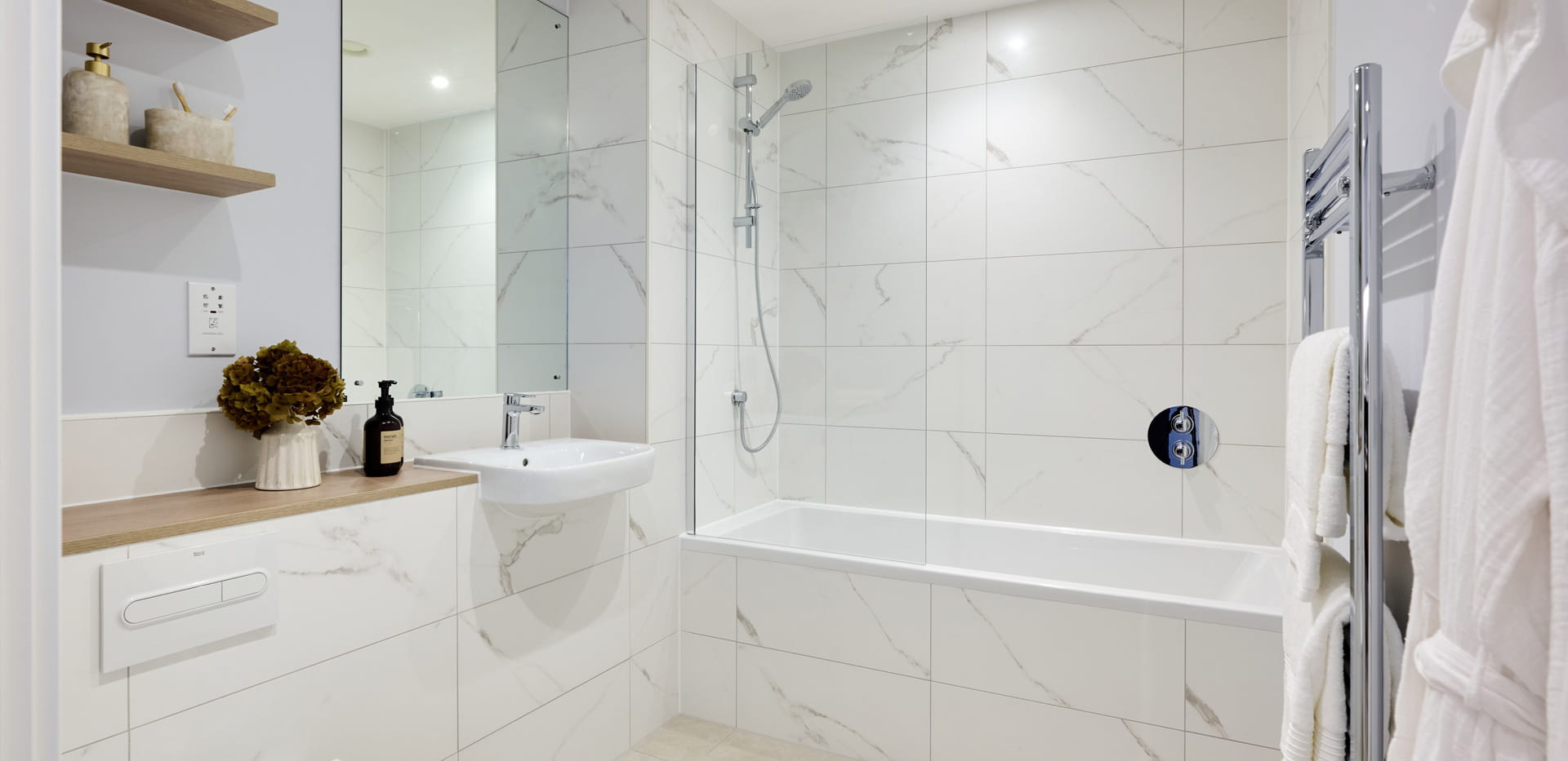 bathroom with shower over bath, wash basin with mirror, heated towel rack and shelving.