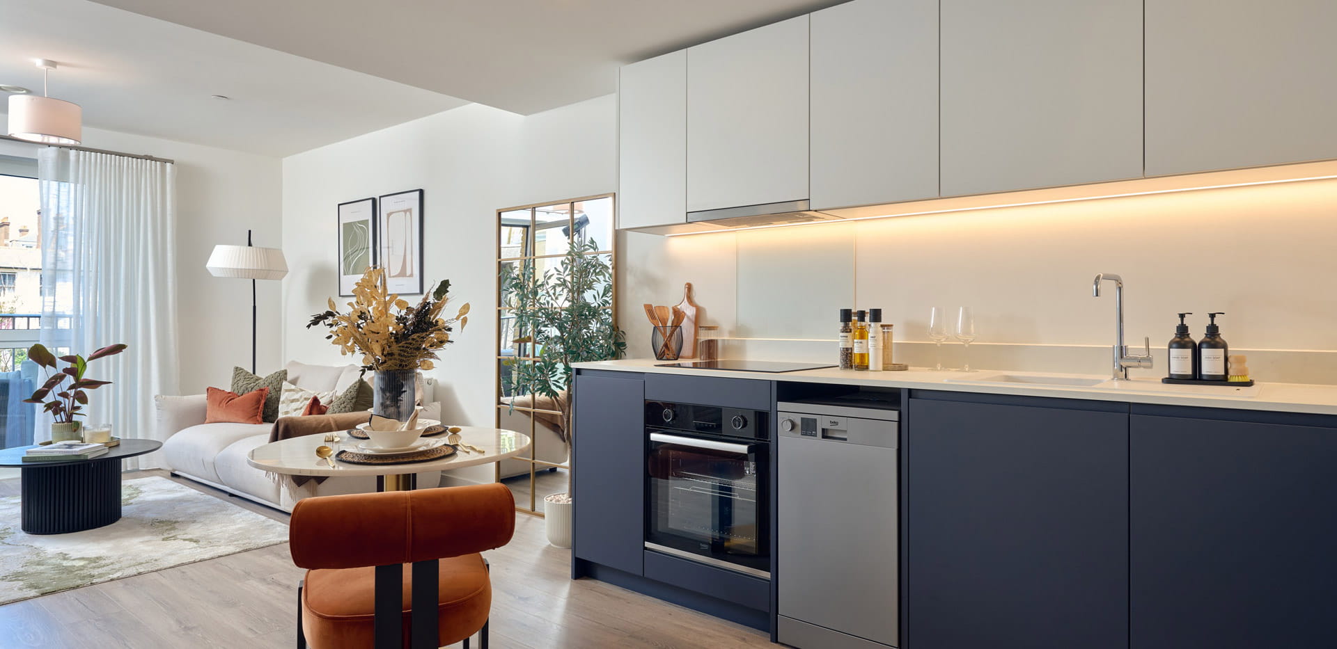 Kitchen dining space with navy blue and light grey panels, cupboards, white countertops.