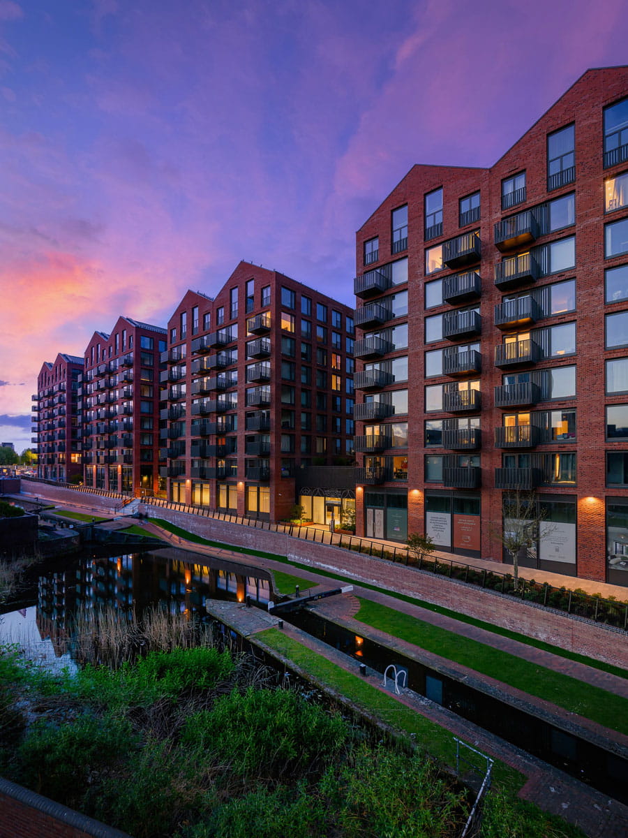 CGI of new build flats with canal in the foreground, taken at dusk or dawn