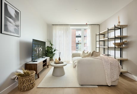 Contemporary designed living space with sofa and coffee table, ample natural lighting from tall windows.