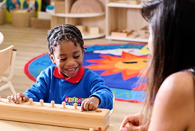 An image of a practitioner and a child at nursery playing and learning
