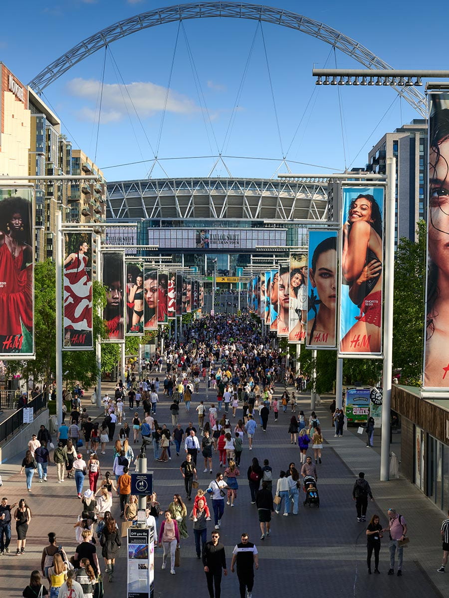 An image of Wembley Stadium with people walking along the path