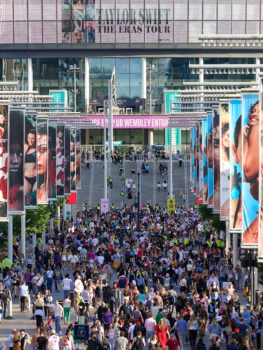 An image of Wembley Stadium with people walking along the path