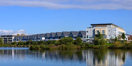 An exterior image of Green Park Village with the lake in the foreground