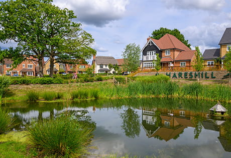 Pond and tree in foreground, new build homes in the background with a sign which reads 'Hareshill'