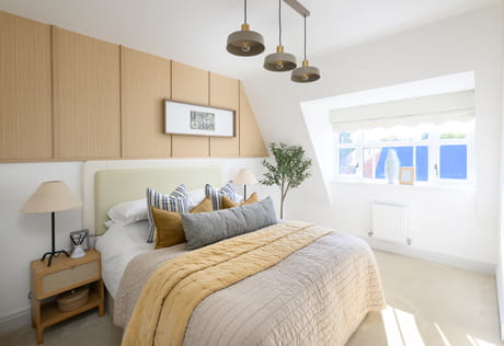 Attic loft bedroom with slanted roofing, decorated in neutral tones, ample natural lighting from wide windows.