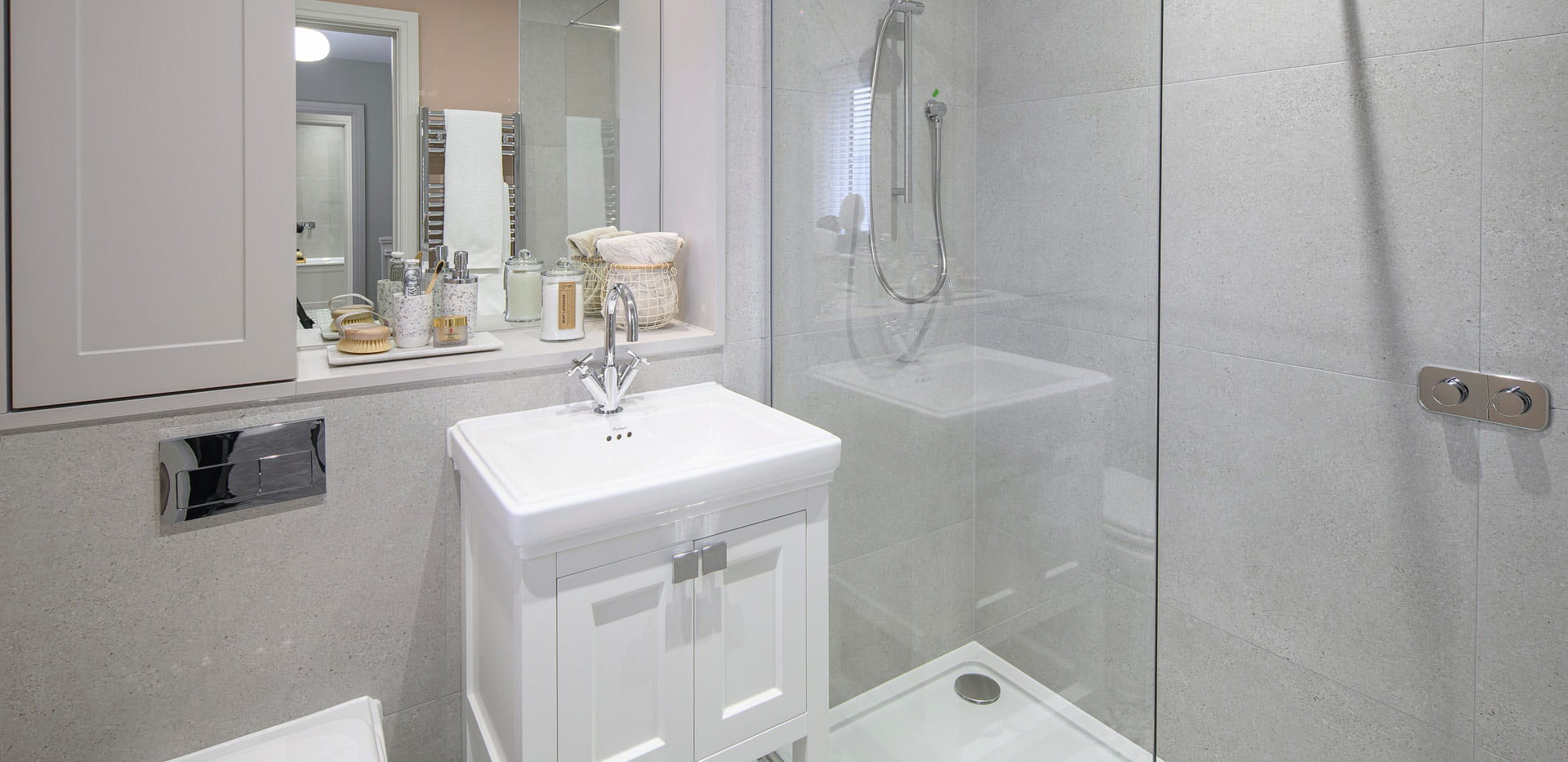 Shower room with white wash basin, wall mirror, cupboard with grey tiled walls
