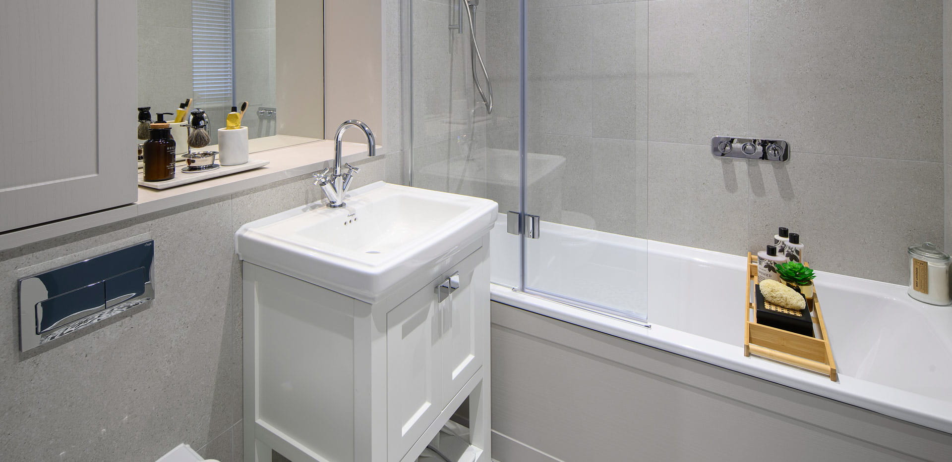 Shower over bath, bath tray and accessories, white sink and grey tiled walls