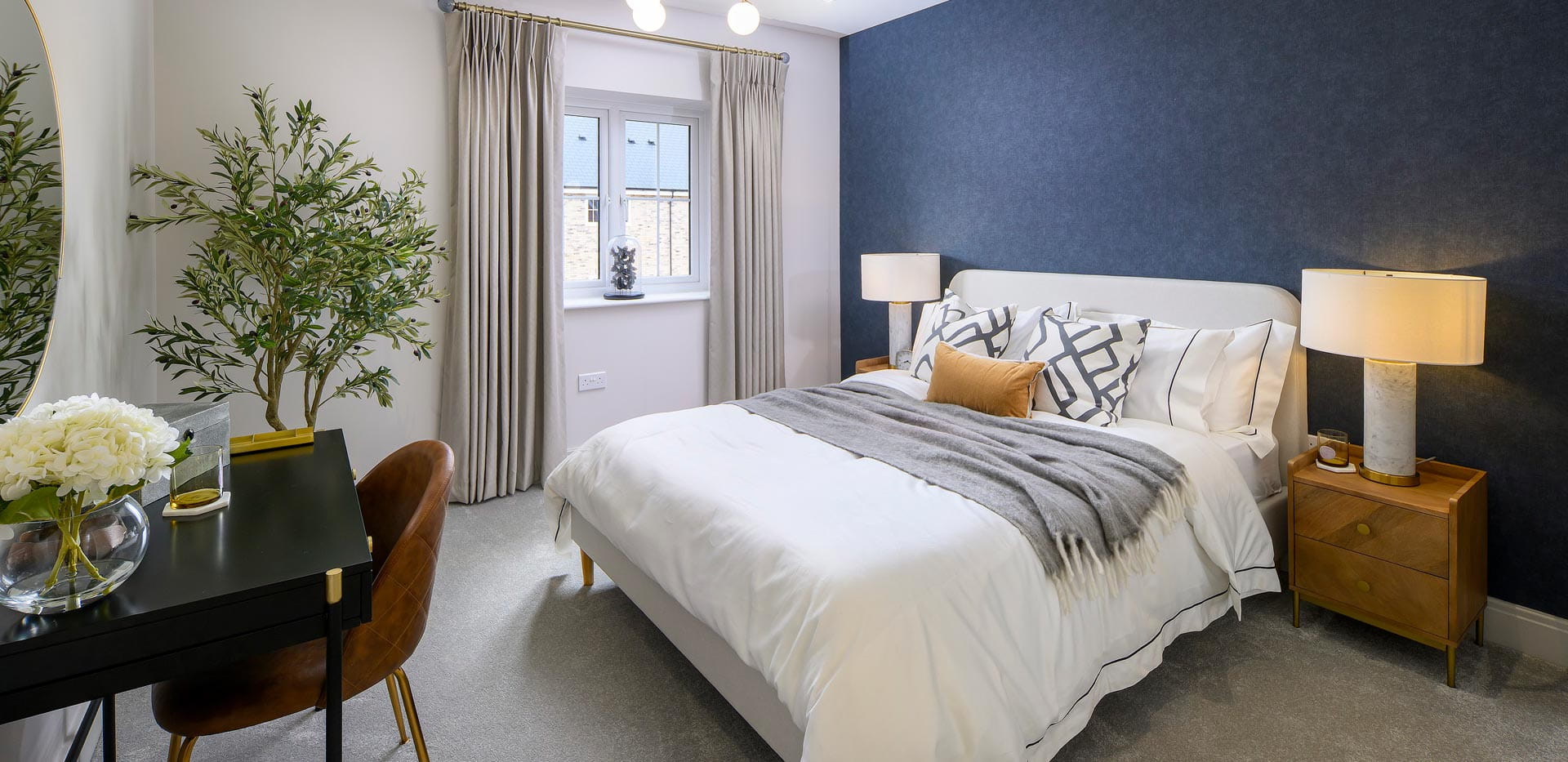 Double bed with navy blue painted wall and white wall, bedside tables and vanity table