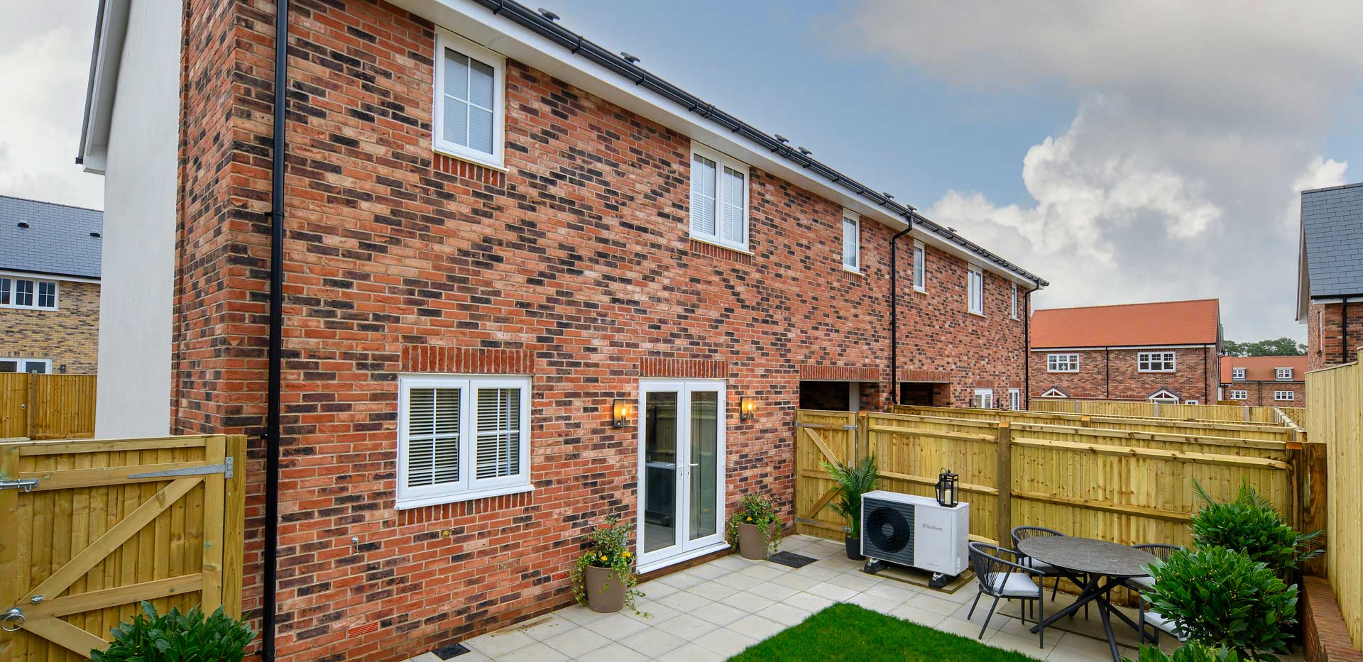 Exterior rear garden with fencing, heat pump, outdoor furniture, grassed and paved area