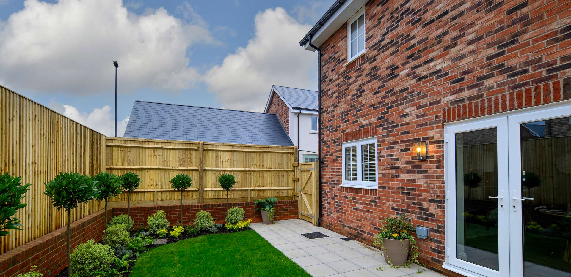 Exterior rear garden with patio doors, fencing, grassed and paved area