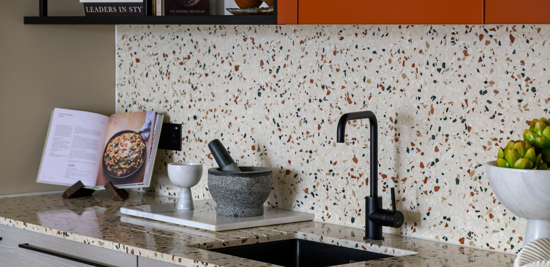 Closeup of kitchen counters with spotted splashback tiles.