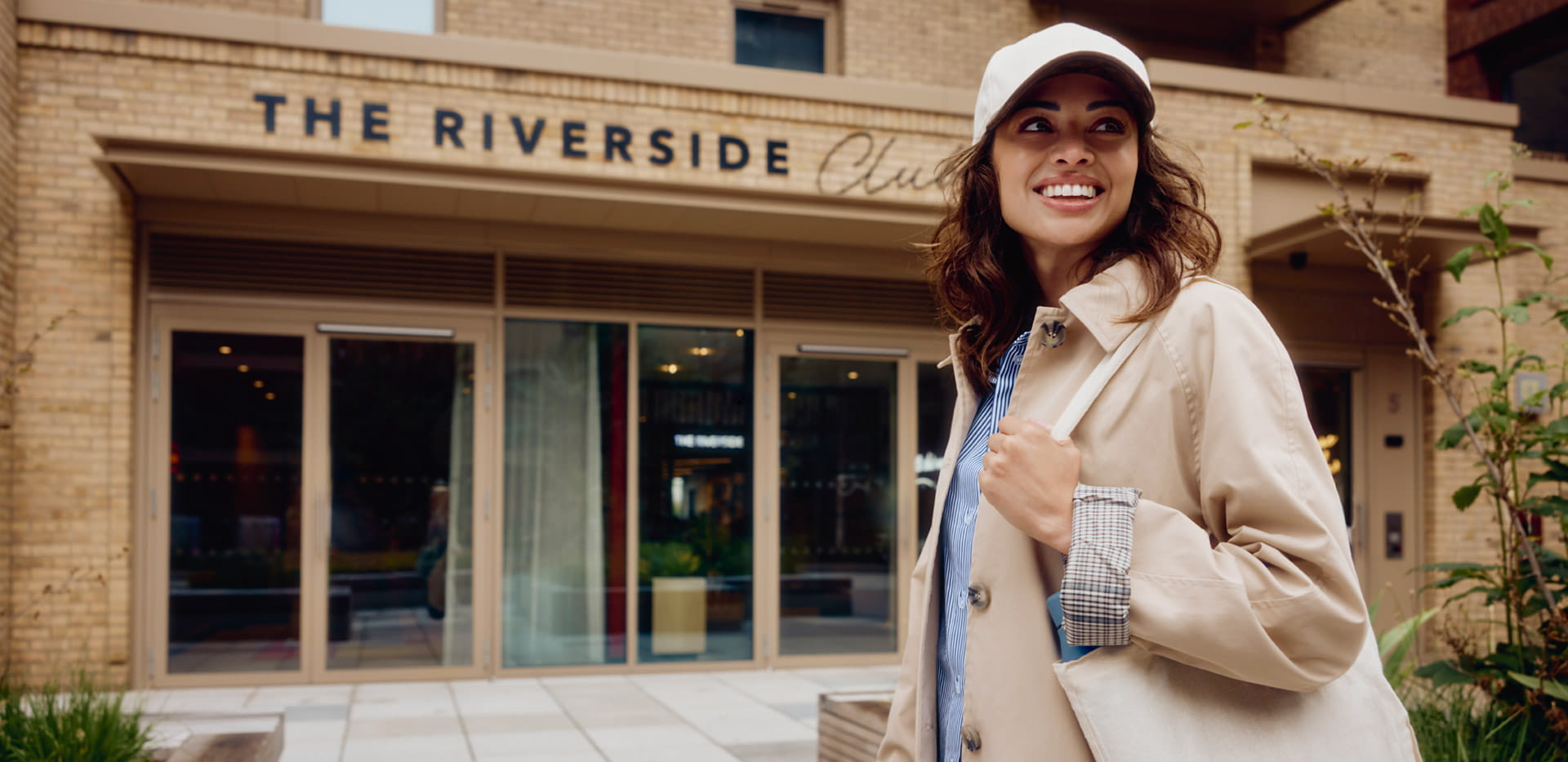 Female smiling and posing in front of Riverside Club establishment street entrance.