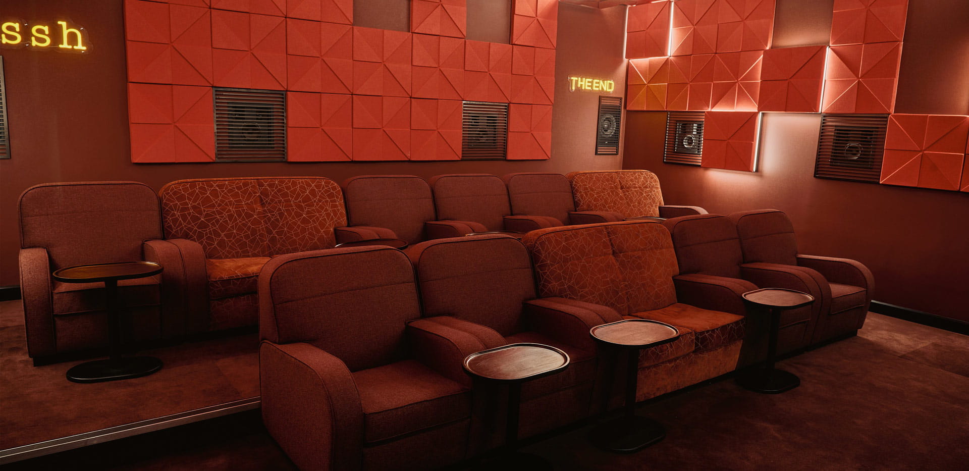 Private, indoor cinema screening room decorated in shades of red.
