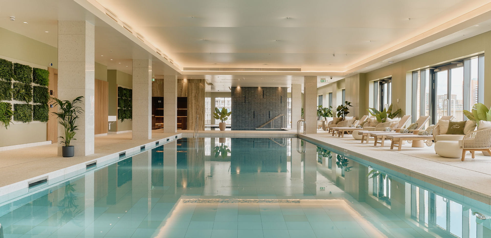 A view down a swimming pool with lounge chairs to the side.