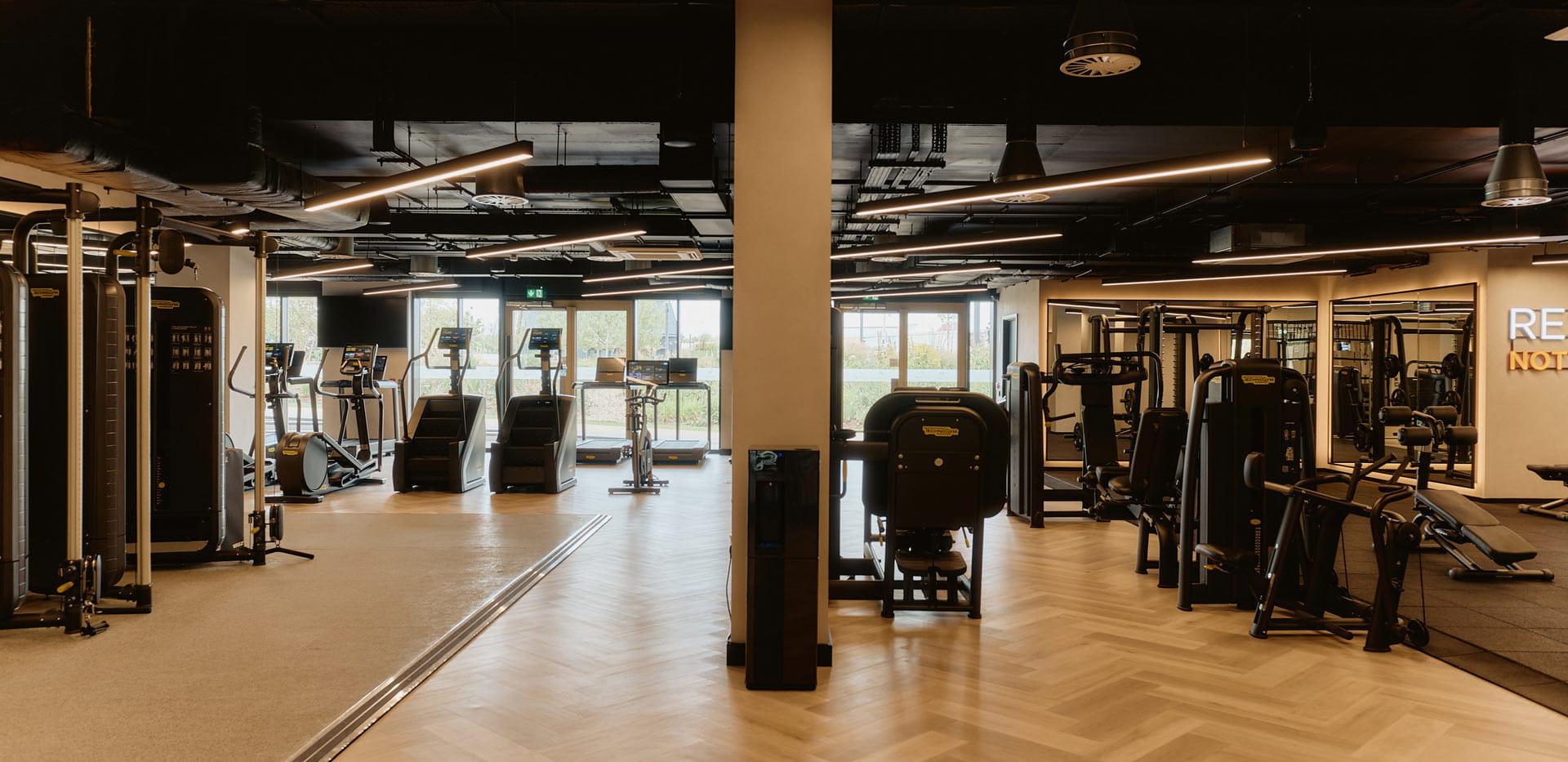 Indoor gym with wall mirrors, cardio and weights machines.