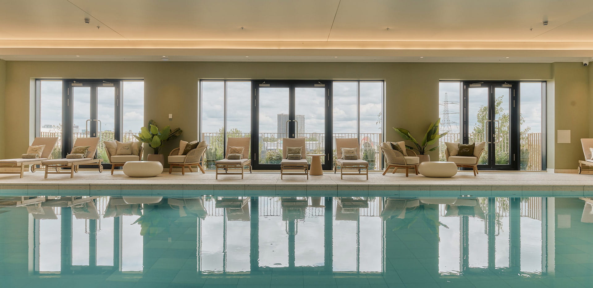 View across a swimming pool and sun lounge deck chairs.