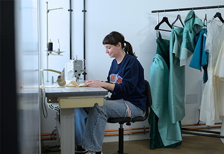 Female working on clothing fabric sewing machine.