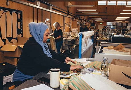 Female working on a worktable with clothing textile fabric.