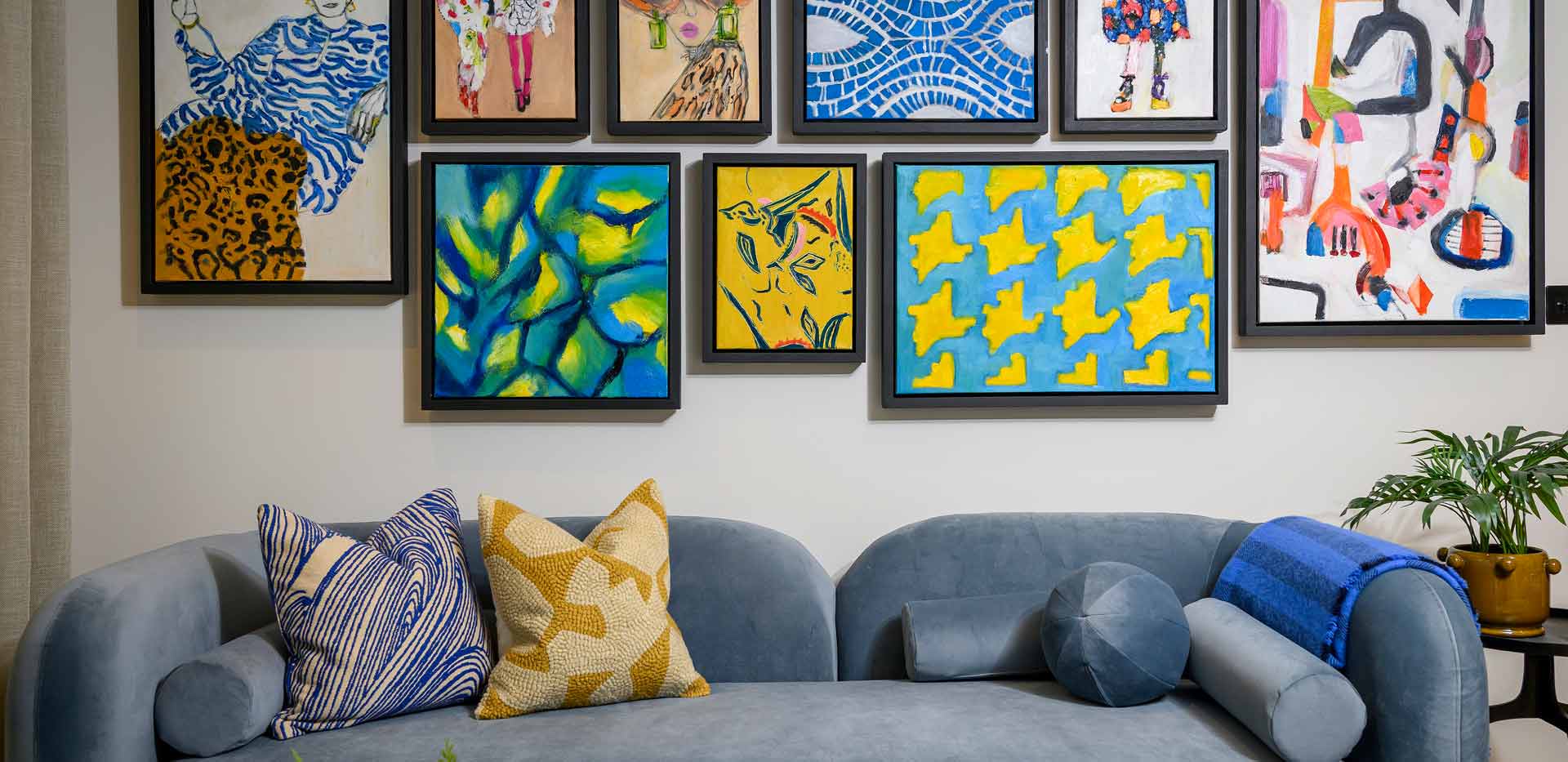 Blue sofa against grey wall with abstract wall hangings