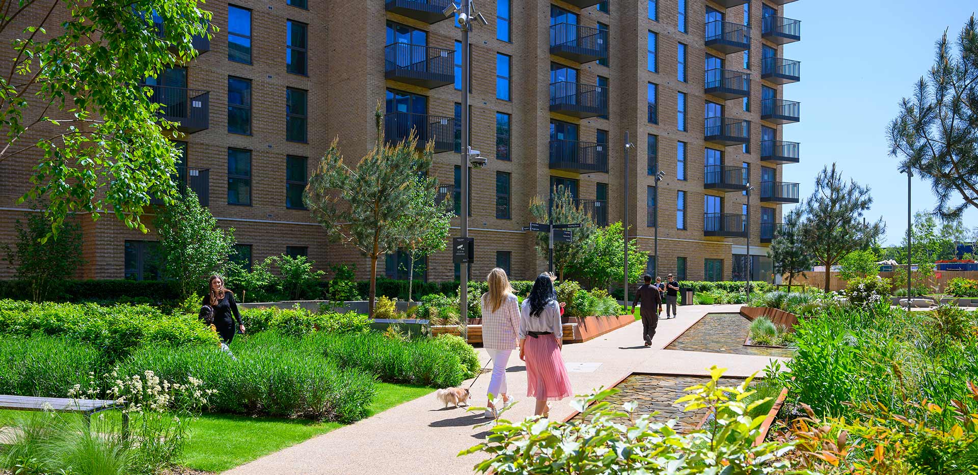 Image of residents walking alongside Aquifer House on a warm sunny day