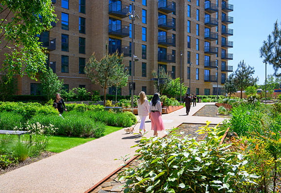 Image of residents walking through the landscaped gardens on a warm sunny day
