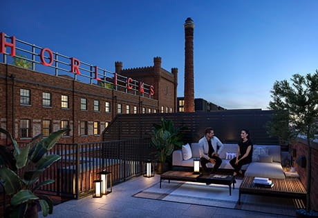An image of a couple sat on their roof terrace with the Horlicks Factory in the background