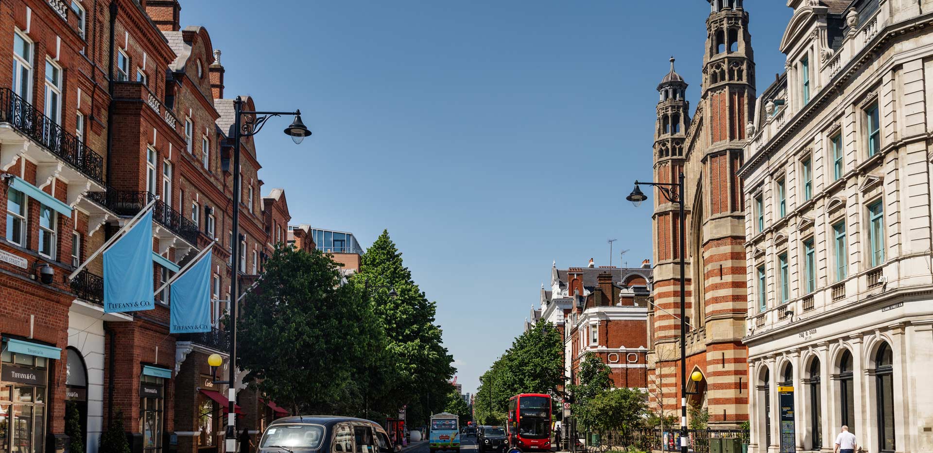 View of busy London traffic along street lined with shops