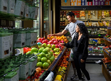 Two people shopping in the fruit and veg aisle