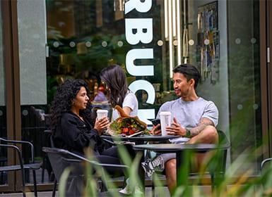 Two people enjoying beverages outside a Starbucks coffee shop