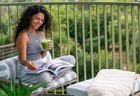 Woman sitting on her balcony enjoying a matcha